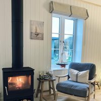 Cosy living room with a fireplace, chair, and window view with roman blind