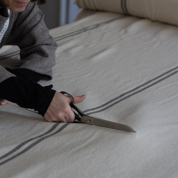 natural grainsack fabric with stripes being cut on a cutting table