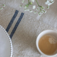Teacup with a white interior on a textured surface with a floral arrangement.