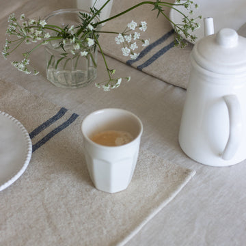 Tea cup with teapot and flowers on a tablecloth