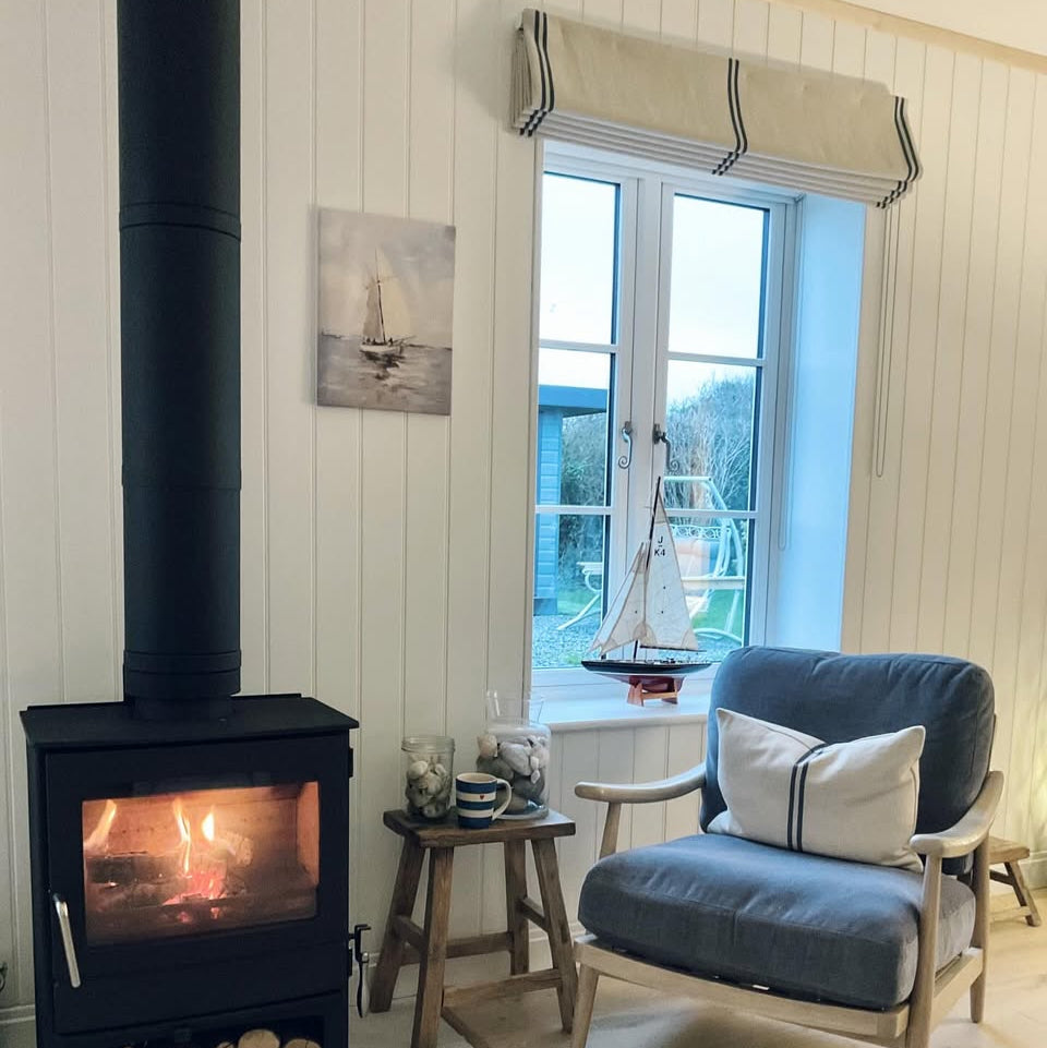 Cosy living room with a fireplace, chair, and window view with roman blind