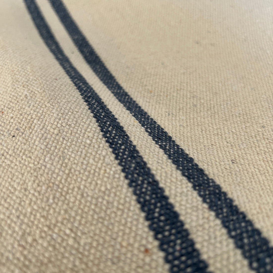 Close-up of a textured fabric with blue stripe on a neutral background