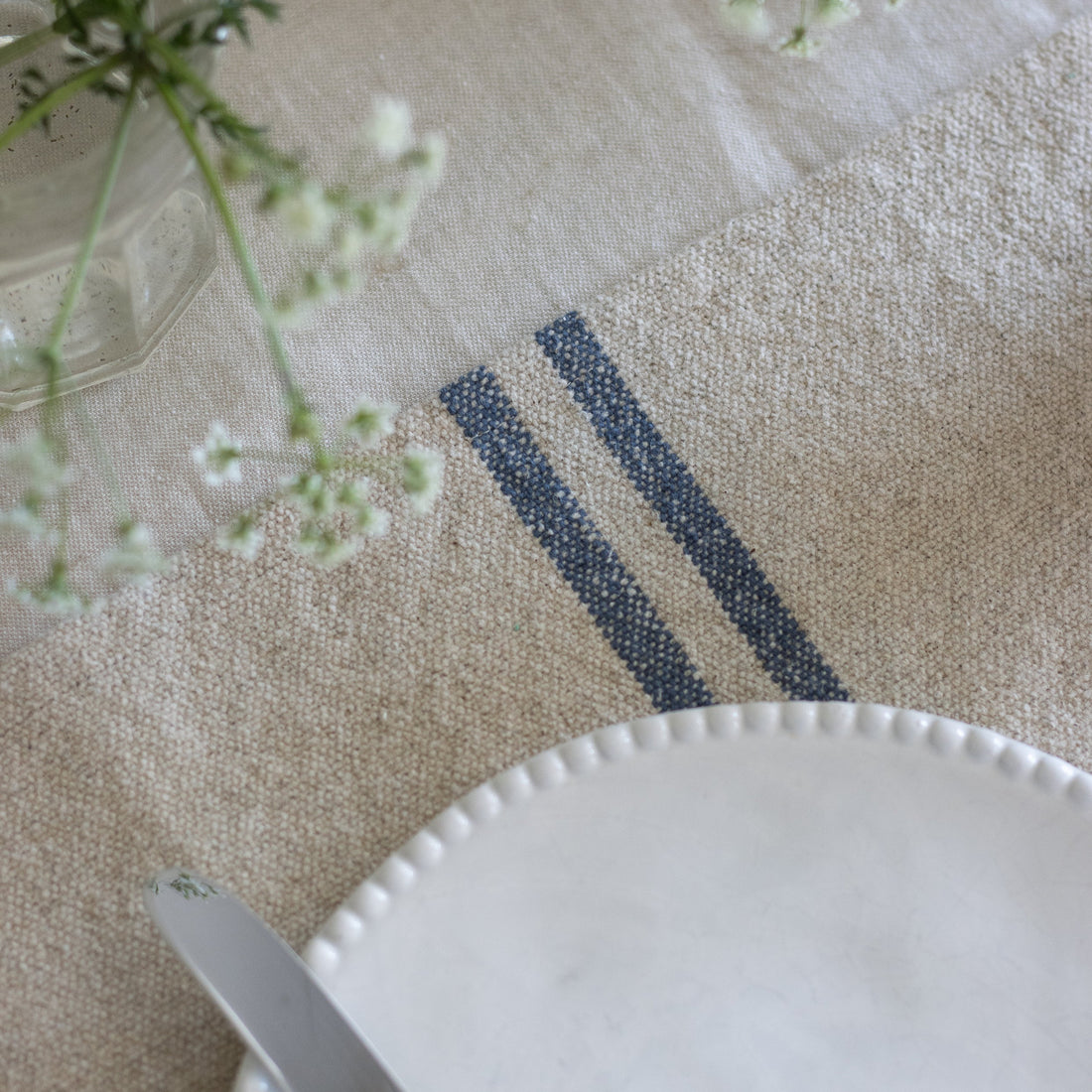 Close-up of a textured surface with a white plate and greenery